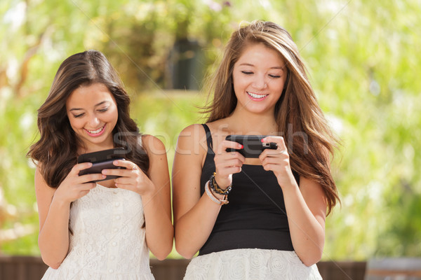 Two Expressive Mixed Race Girlfriends Using Their Smart Cell Pho Stock photo © feverpitch