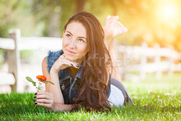 Attractive Mixed Race Girl Holding Flower Portrait Laying in Gra Stock photo © feverpitch