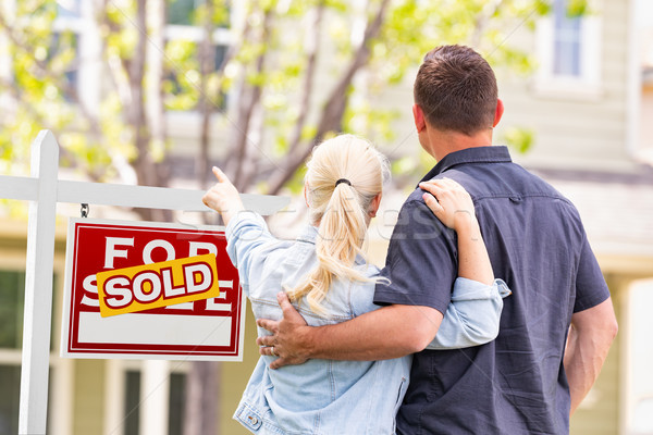 Caucasian Couple Facing and Pointing to Front of Sold Real Estat Stock photo © feverpitch