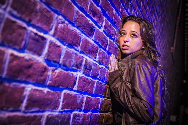 Frightened Pretty Young Woman Against Brick Wall at Night Stock photo © feverpitch