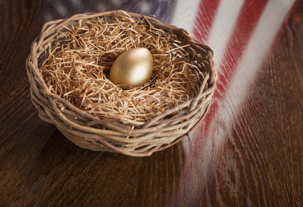 Stock photo: Golden Egg in Nest with American Flag Reflection on Table