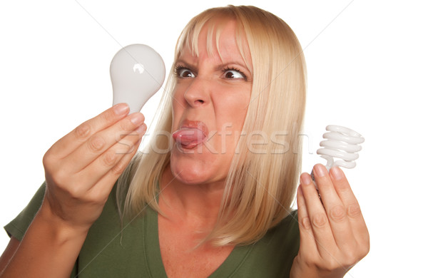 Stock photo: Funny Woman Holding Energy Saving and Regular Light Bulbs