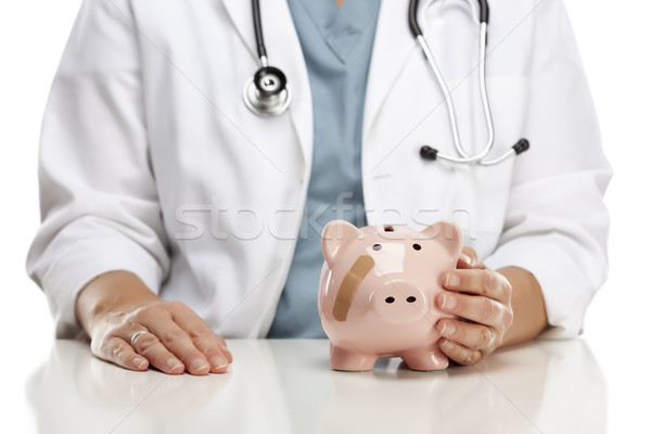 Doctor Holding Caring Hand on a Piggy Bank with Bandage Stock photo © feverpitch