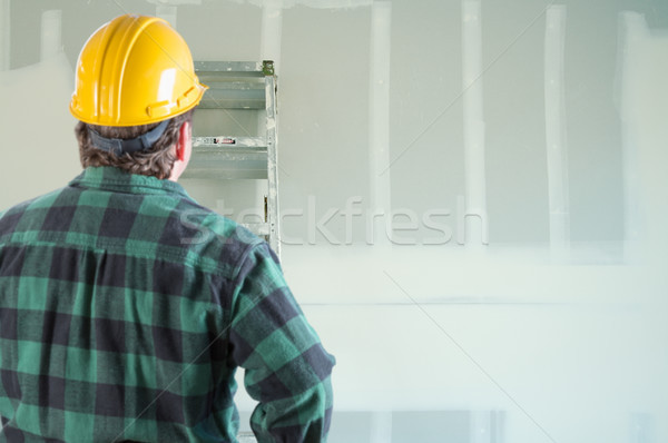 Contractor in Hard Hat Looking at Drywall. Stock photo © feverpitch