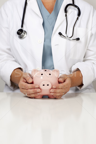 Doctor with Caring Hands on a Piggy Bank Stock photo © feverpitch