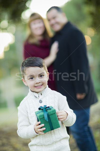 Stock photo: Mixed Race Boy Holding Gift In Front with Parents Behind