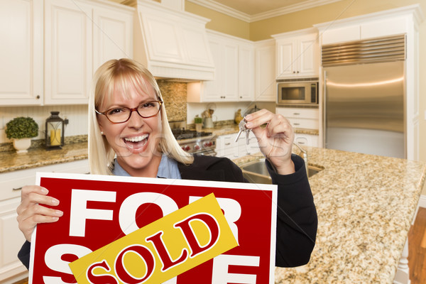 Young Woman Holding Sold Sign and Keys Inside New Kitchen Stock photo © feverpitch