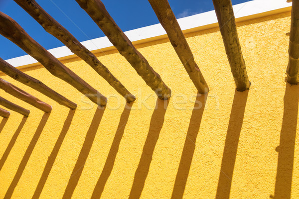 Abstract Wood Post Beams and Bright Yellow Wall Against Blue Sky Stock photo © feverpitch