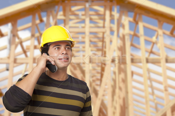 Hispanic Male Contractor on Phone in Front of House Framing Stock photo © feverpitch