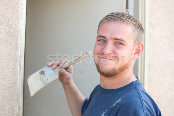 Young Caucasian Man Smiling As He Is Painting House Stock photo © feverpitch