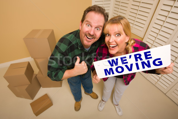 Stock photo: Goofy Couple Holding We're Moving Sign Surrounded by Boxes