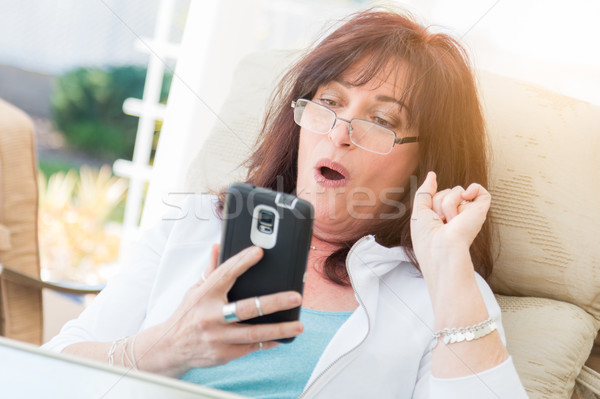 Shocked Middle Aged Woman Gasps While Using Her Smart Phone Stock photo © feverpitch