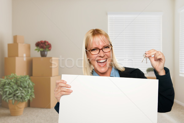 Woman with Blank Sign and House Key in Empty Room with Packed Mo Stock photo © feverpitch