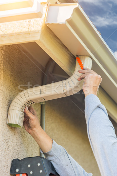 Worker Attaching Aluminum Rain Gutter and Down Spout to Fascia o Stock photo © feverpitch