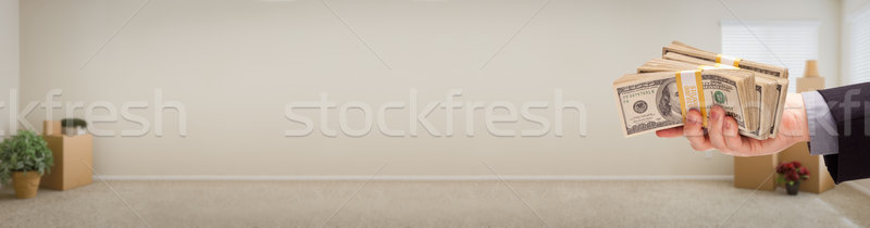 Hand Holding Stacks of Money Inside Empty Room with Boxes Banner Stock photo © feverpitch