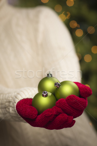 Stock photo: Woman Wearing Seasonal Red Mittens Holding Green Christmas Ornam