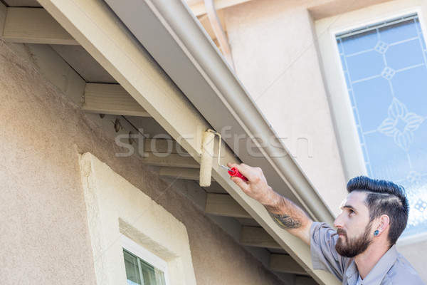 Stock photo: Professional Painter Using Small Roller to Paint House Fascia