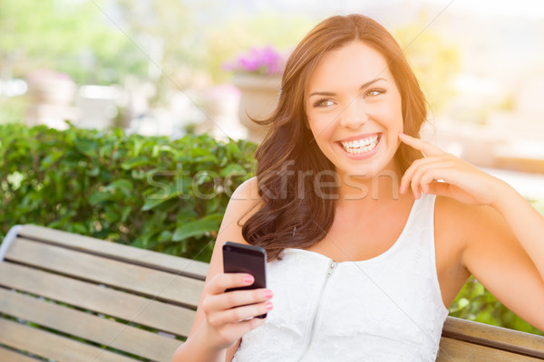 Smiling Young Adult Female Texting on Cell Phone Outdoors Stock photo © feverpitch