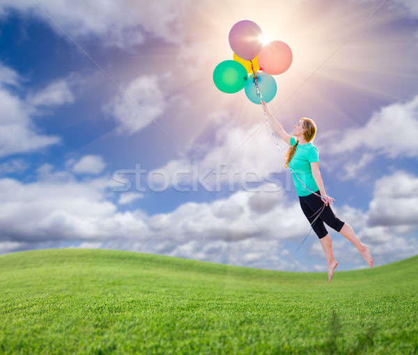 Stock photo: Young Girl Being Carried Up and Away By Balloons That She Is Hol