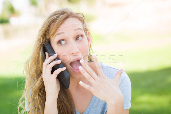 Stunned Young Woman Outdoors Talking on Her Smart Phone. Stock photo © feverpitch