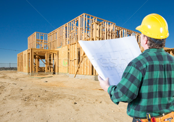 Contractor with Plans and Hard Hat Looking At New House Framing  Stock photo © feverpitch