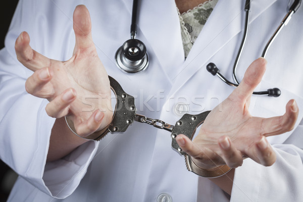 Doctor or Nurse In Handcuffs Wearing Lab Coat and Stethoscope Stock photo © feverpitch