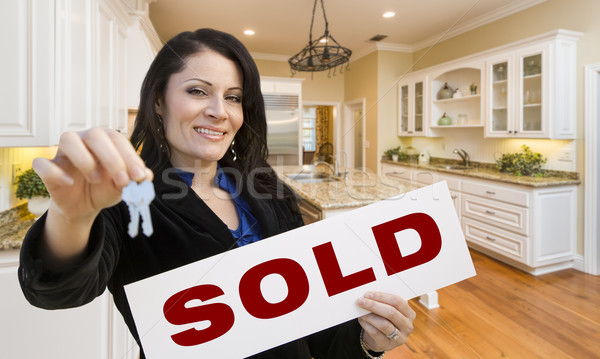 Hispanic Woman In Kitchen Holding House Keys and Sold Sign Stock photo © feverpitch