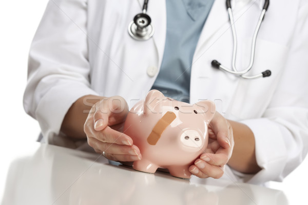 Doctor Holding Caring Hands on a Piggy Bank with Bandage Stock photo © feverpitch