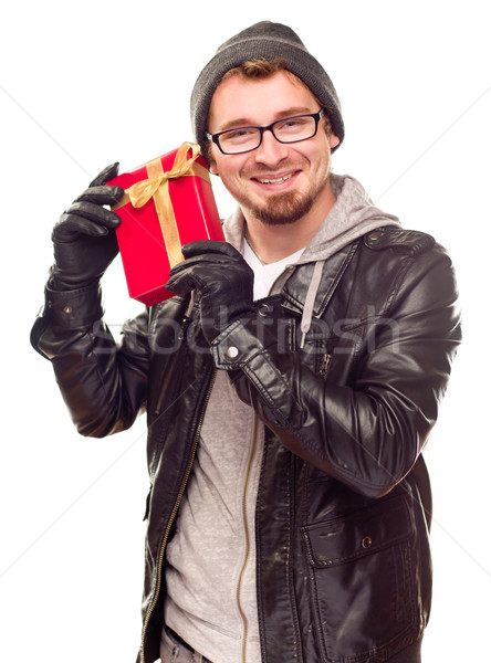 Warmly Dressed Young Man Holding Wrapped Gift To His Ear Stock photo © feverpitch