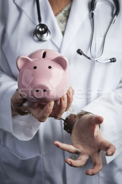Stock photo: Doctor In Handcuffs Holding Piggy Bank Wearing Lab Coat, Stethos