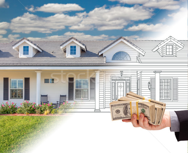 Hand Holding Stack of Money Over House Drawing Gradating Into Ph Stock photo © feverpitch