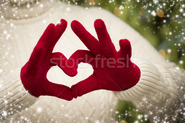 Stock photo: Woman Wearing Red Mittens Holding Out a Heart Hand Sign