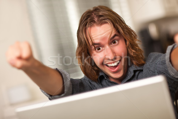 Stock photo: Cheering Young Man Using Laptop Computer