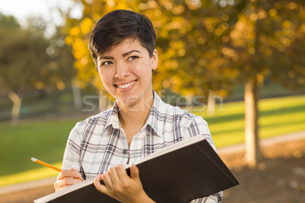 Mixed Race Young Female Holding Sketch Book and Pencil Outdoors Stock photo © feverpitch