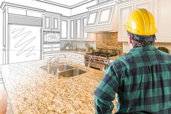 Stock photo: Male Contractor with Hard Hat Looking At Custom Kitchen Drawing 