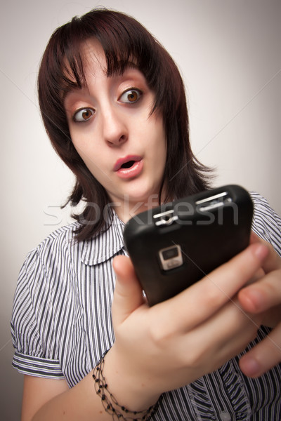 Stunned Brunette Woman Using Cell Phone Stock photo © feverpitch