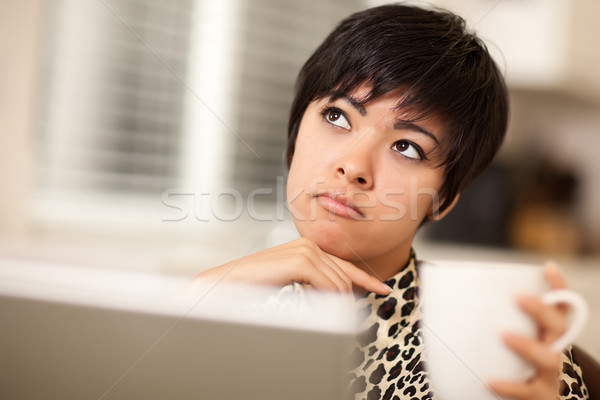 Pretty Mixed Race Woman Holding Cup Using Laptop Stock photo © feverpitch