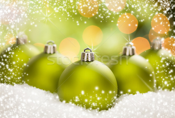 Stock photo: Green Christmas Ornaments on Snow Over an Abstract Background