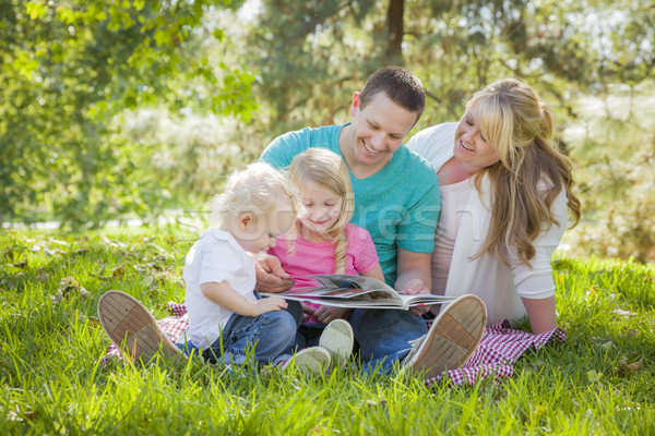 Stock photo: Young Family Enjoys Reading a Book in the Park