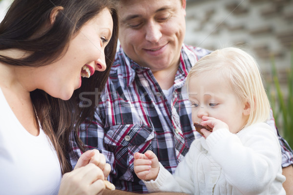 Adorable Little Girl Eating a Cookie with Mommy and Daddy Stock photo © feverpitch