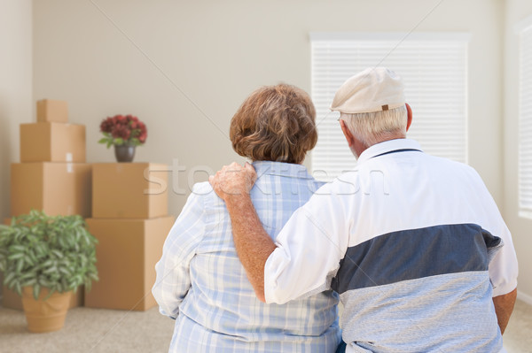 Senior Couple Facing Empty Room with Packed Moving Boxes and Pot Stock photo © feverpitch