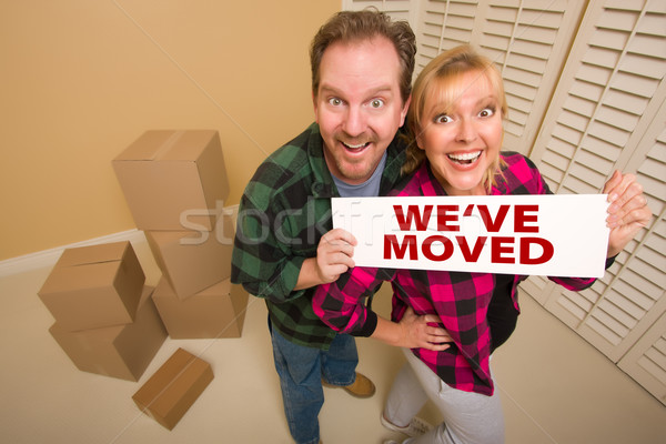 Goofy Couple Holding We've Moved Sign Surrounded by Boxes Stock photo © feverpitch