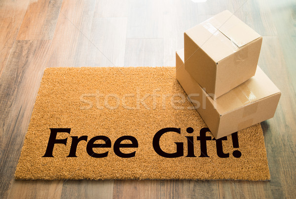 Stock photo: Free Gift Welcome Mat On Wood Floor With Shipment of Boxes