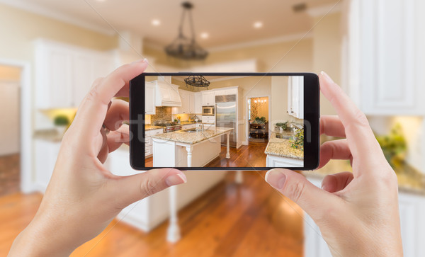 Female Hands Holding Smart Phone Displaying Photo of Kitchen Beh Stock photo © feverpitch
