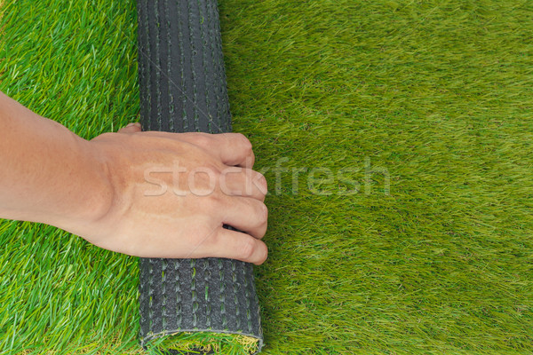 Artificial turf green grass roll with hand Stock photo © FrameAngel