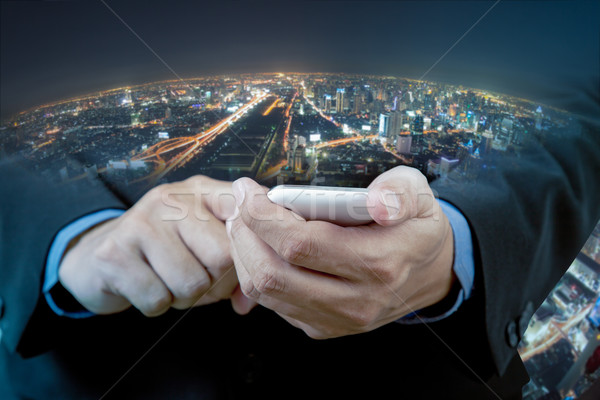 Businessman touch smart phone in hand with blur background of ci Stock photo © FrameAngel
