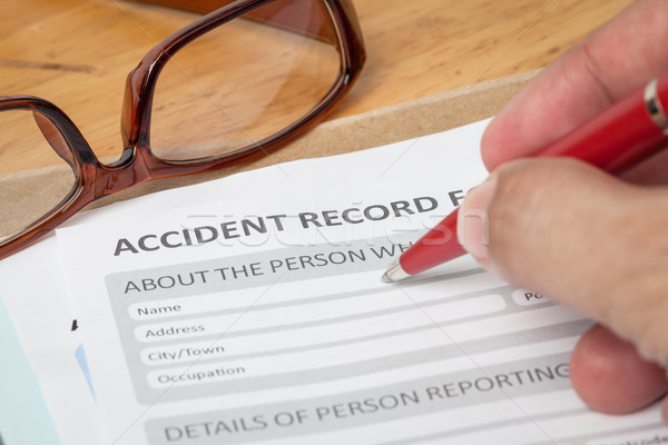 Accident report application form and human hand with pen on brow Stock photo © FrameAngel