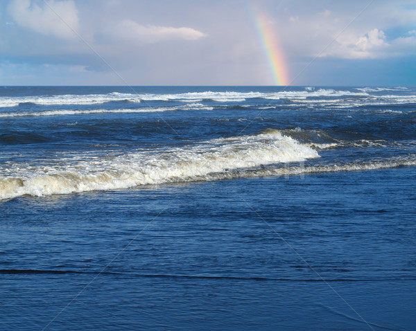 Ocean Waves Breaking on Shore with a Partial Rainbow in the Background  Stock photo © Frankljr