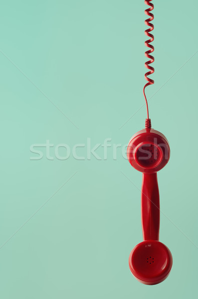 Stock photo: Retro Red Telephone Receiver Hanging by Spiral Cord on Aqua Back