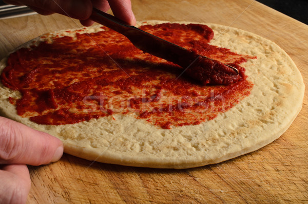 Hand Spreading Tomato Base on Pizza Stock photo © frannyanne